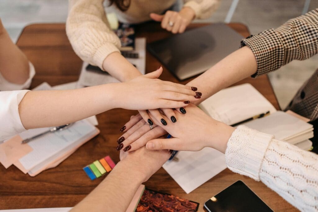 a group of coworkers all putting their hands together 